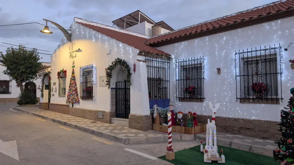 Casa andaluza decorada con luces de Navidad en una calle tranquila, con fachadas blancas, adornos tradicionales y ambiente cálido del sur.